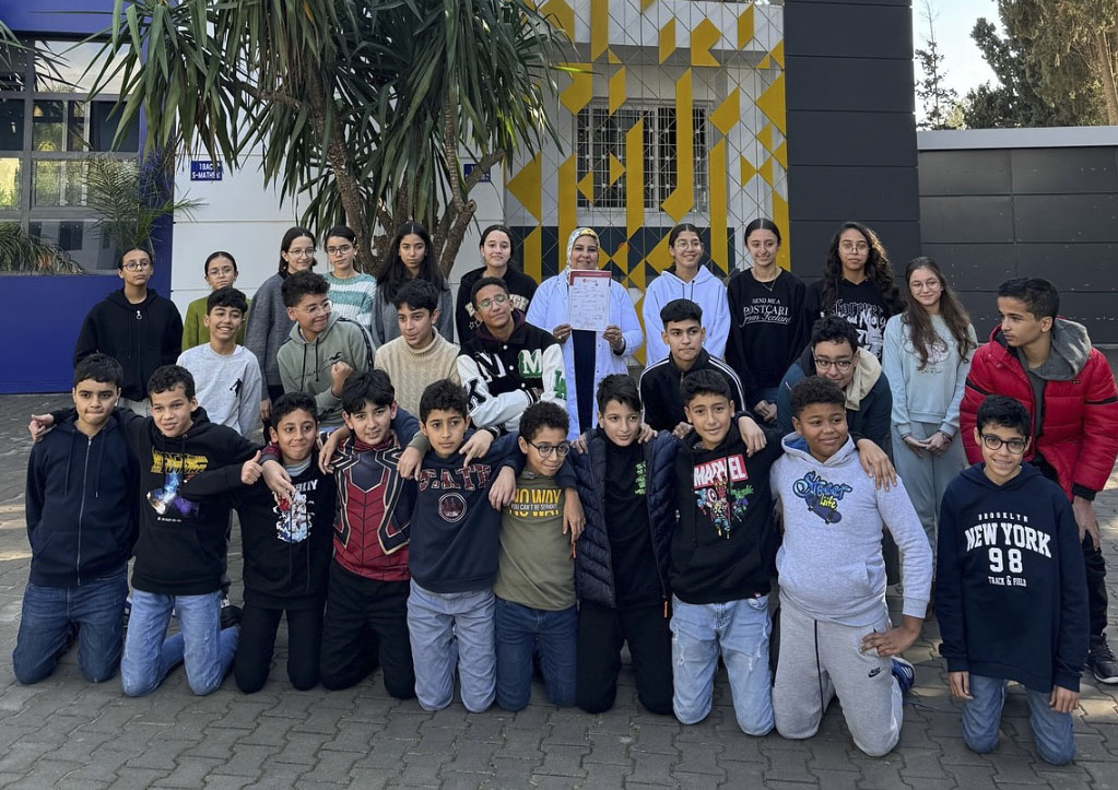 Photo d’une classe avec un enseignant et des élèves en interaction.